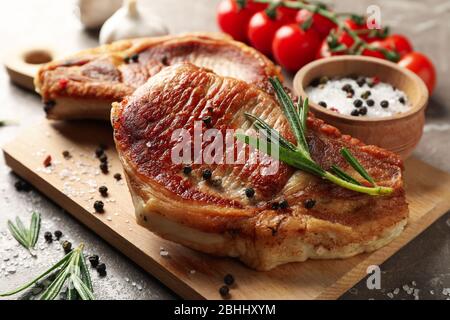 Zusammensetzung mit gebratenen Steaks und Zutaten auf grauem Hintergrund. Grillgerichte Stockfoto