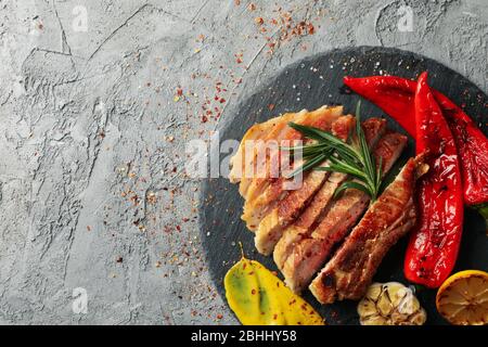 Tablett mit gehacktem Schweinefleisch Steak und Gemüse auf grauem Hintergrund. Grillgerichte Stockfoto