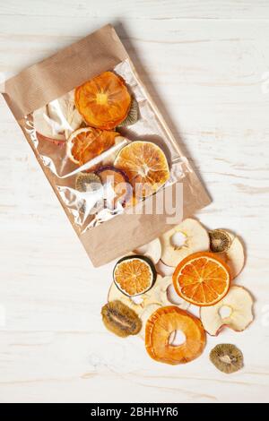Obstschnitzel in einem Papiertütchen auf hellem Holzhintergrund. Blick von oben Stockfoto