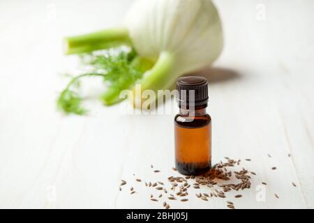 Fenchel ätherisches Öl in einer Glasflasche, frischer Fenchel auf hellem Holzhintergrund Stockfoto