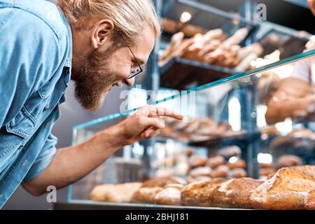 Kleinunternehmen. Mann in Gläsern Kunde steht in Bäckerei-Shop Auswahl Gebäck lächelnd aufgeregt Stockfoto
