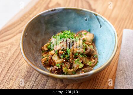 Gebratene Pilze mit Sojasoße und Frühlingszwiebeln auf dem Restauranttisch, asiatisches Gericht Stockfoto