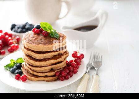 Vollkorn-Pfannkuchen mit Beeren auf weißem Tisch, gesundes Frühstück Stapel von Pfannkuchen. Kopieren Sie den Bereich auf weißem Hintergrund Stockfoto