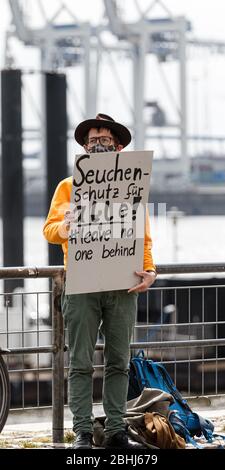 Hamburg, Deutschland. April 2020. Ein Demonstrator hält ein Schild mit der Aufschrift "epidemischer Schutz für alle! Lass keine ne hinter'. Aktivisten der Hilfsorganisation Seebrücke demonstrieren in einer Kette von 20 Standorten von der Fischauktionsallee bis zu den Deichtorhallen mit Schildern und Transparenten für eine Auflösung der Flüchtlingslager in Griechenland. Quelle: Markus Scholz/dpa/Alamy Live News Stockfoto