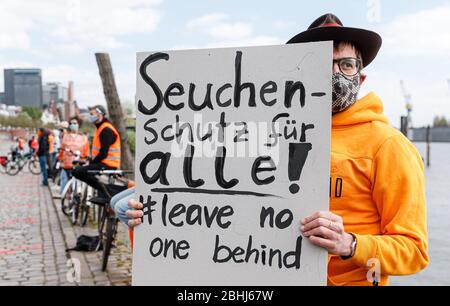 Hamburg, Deutschland. April 2020. Ein Demonstrator hält ein Schild mit der Aufschrift "epidemischer Schutz für alle! Lass keine ne hinter'. Aktivisten der Hilfsorganisation Seebrücke demonstrieren in einer Kette von 20 Standorten von der Fischauktionsallee bis zu den Deichtorhallen mit Schildern und Transparenten für eine Auflösung der Flüchtlingslager in Griechenland. Quelle: Markus Scholz/dpa/Alamy Live News Stockfoto