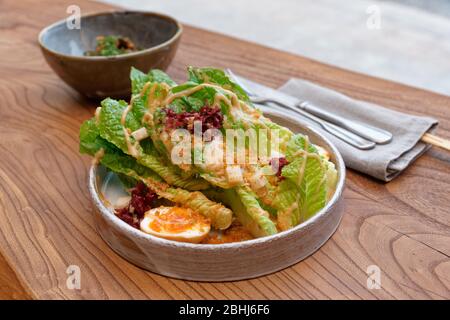 Caesar Salat auf asiatische Art zubereitet - kreative Fusion-Küche auf dem Restauranttisch Stockfoto