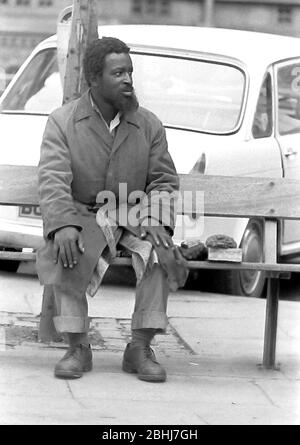 Das tägliche Leben auf den Straßen in Manchester, England, Großbritannien im Jahr 1974. Ein afro-karibischer Mann sitzt auf einer Bank am Albert Square im Zentrum von Manchester. Stockfoto