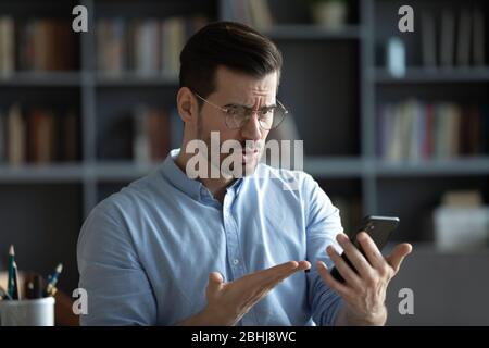 Unglücklich irritierten Mann trägt Brille mit Problem mit Smartphone Stockfoto