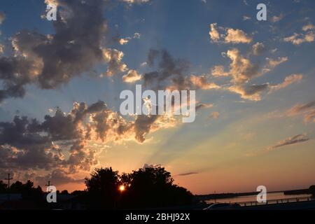 Himmel und Wolken sind in warmen Farben des Sonnenuntergangs gemalt und die Landschaften sind auf der Erde dargestellt Stockfoto