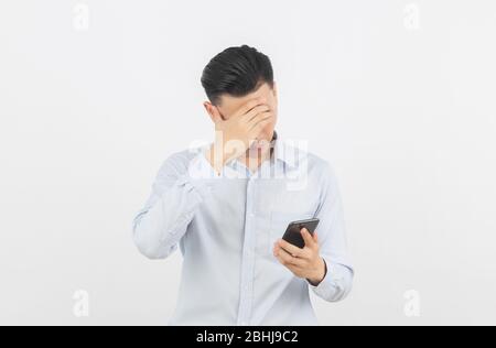 Junge asiatische Geschäftsmann unglücklich und frustriert mit etwas auf dem Smartphone. Negativer Gesichtsausdruck auf weißem Hintergrund isoliert. Stockfoto