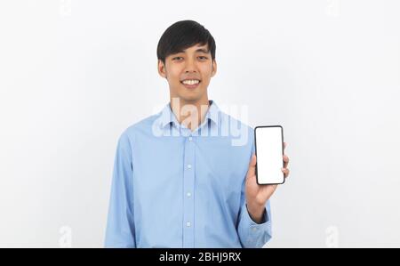 Junge gut aussehende asiatische Geschäftsmann zeigt Smartphone mit leerem Bildschirm und lächelnd isoliert auf weißem Hintergrund. Stockfoto