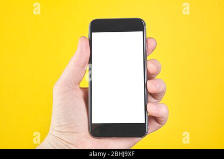 Halten Sie das Smartphone auf gelbem Hintergrund. Nahaufnahme Stockfoto