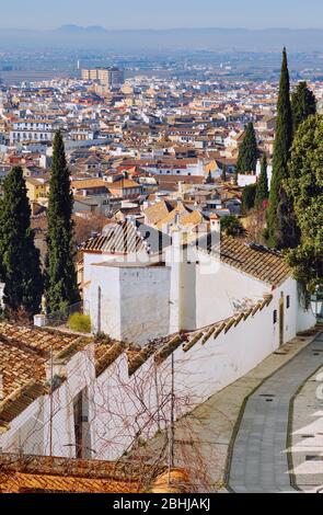 Leere charmante schmale Straße zwischen Wohnhäusern, die bis zu den Bergen der Sierra Nevada führen, hinunter zur Altstadt von Granada Resort Stadt. Spanien Stockfoto