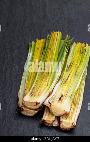 Gegrillte Babylauch auf schwarzem Steingrund Stockfoto