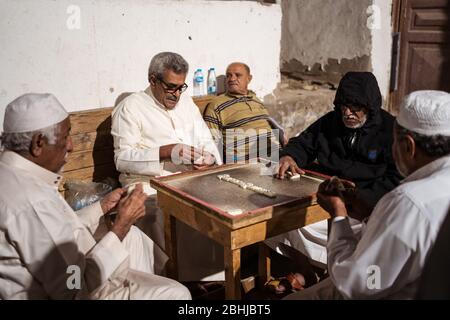 Dschidda / Saudi-Arabien - 16. Januar 2020: Alte muslimische Männer spielen nachts Dominosteine in den Straßen des historischen Al-Balad Stockfoto