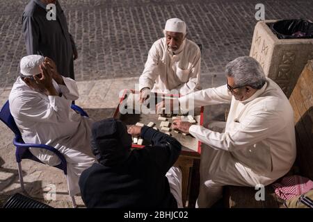 Dschidda / Saudi-Arabien - 16. Januar 2020: Alte muslimische Männer spielen nachts Dominosteine in den Straßen des historischen Al-Balad Stockfoto