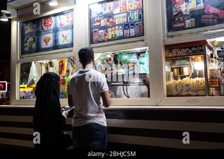 Jeddah / Saudi Arabien - 16. Januar 2020: Muslimisches Paar wartet vor dem Lebensmittelstand auf der Parkpromenade vor dem König Fahds Brunnen Stockfoto