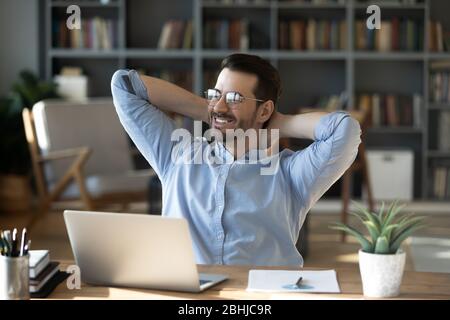 Lächelnder Geschäftsmann, der sich zurück in den Stuhl lehnt und von der Zukunft träumt Stockfoto