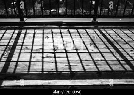 Schwarz-Weiß-Aufnahme von Schatten auf dem Geländer, die in der späten Nachmittagssonne ansprechende gerade Linien auf einen Holzbalkon werfen. Ottawa, Ontario, Kanada. Stockfoto