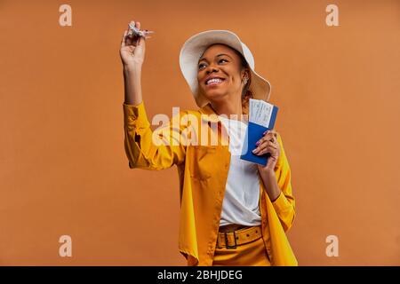 Glückliche Dame im Hut mit einem Flugzeug mit einem Pass mit Tickets. Stockfoto