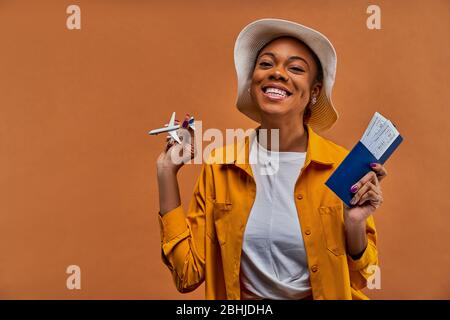 Dame mit einem Lächeln im Hut mit einem Flugzeug mit einem Pass mit Tickets. Stockfoto