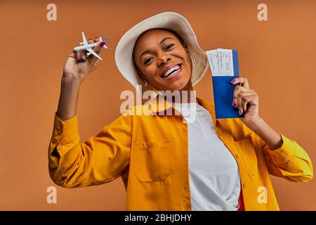 Dame mit einem Lächeln im Hut mit einem Flugzeug mit einem Pass mit Tickets. Stockfoto