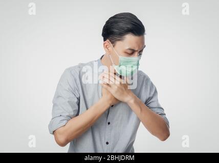 Junge asiatische Geschäftsmann in hygienischen Maske leiden Halsschmerzen, 2019-nCoV oder Coronavirus. Atemwegserkrankungen wie PM 2.5 Kampf und Grippe Stockfoto