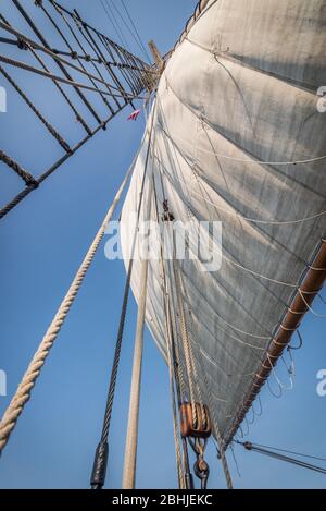 Blick nach oben durch die Takelage auf die Spitze des Mastes auf einem traditionellen hölzernen hohen Schiff mit weißen Segeln Stockfoto