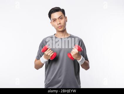 Junge asiatische Mann in Sport-Outfits mit Hanteln trainieren und schauen auf Kamera isoliert auf weißem Hintergrund. Stockfoto