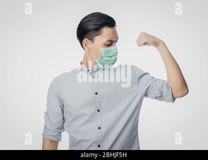 Junge asiatische Geschäftsmann in hygienischen Maske zeigt Stärke, um Infektionen zu verhindern, 2019-nCoV oder Coronavirus. Atemwegserkrankungen in der Luft, wie z. B. PM 2.5 Stockfoto