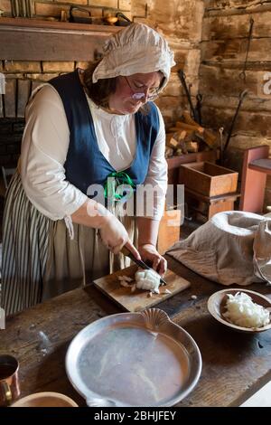 Eine Schauspielerin schneidet Zwiebeln während einer Demonstration der Pionier-Zubereitung im historischen Old Fort Wayne in Fort Wayne, Indiana, USA. Stockfoto