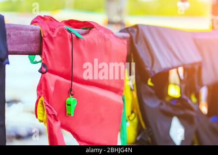 Eine grüne Pfeife mit roter Lebensjacke, die am Geländer um den Gehweg hängt, damit die Passagiere sicher an den Docks sind. Stockfoto