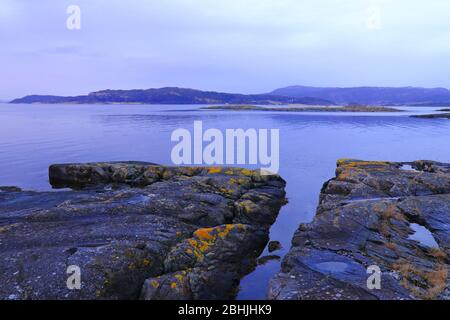 Winteruntergang während der blauen Stunde an den felsigen Ufern des Trondheimsfjords, Flatholmen, Norwegen. Stockfoto