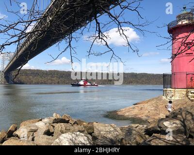 New York, USA. April 2020. New York Feuerwehrboot unterwegs auf dem Hudson River unter George Washington Bridge vom Little Red Lighthouse. Jeffr Stockfoto