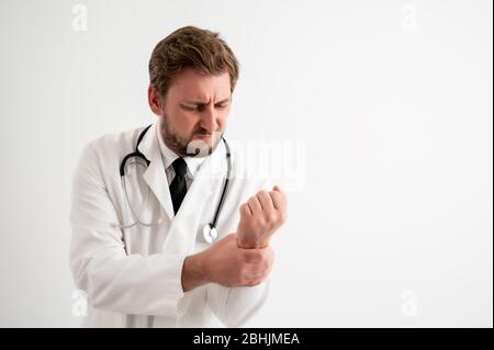 Porträt des männlichen Arztes mit Stethoskop in medizinischer Uniform hat Handgelenkschmerzen posiert auf einem weißen isolierten Hintergrund Stockfoto