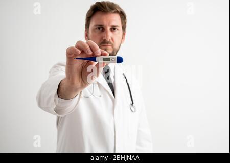 Porträt des männlichen Arztes mit Stethoskop in medizinischer Uniform, das digitales Thermometer auf einem weißen isolierten Hintergrund posiert Stockfoto