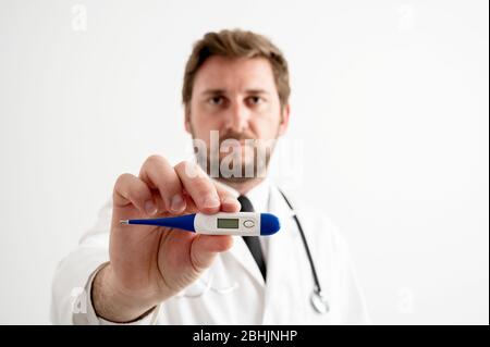 Porträt des männlichen Arztes mit Stethoskop in medizinischer Uniform, das digitales Thermometer auf einem weißen isolierten Hintergrund posiert Stockfoto