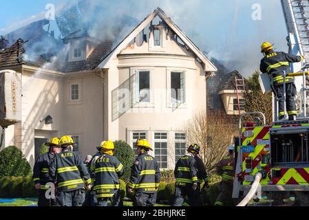 Feuerwehrleute koordinieren die Arbeit bei einem Brand am 84 Castlemere Place, North Andover, Massachusetts. April 2020. Stockfoto