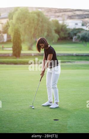 Frau, die Golf auf einem wunderschönen Golfplatz spielt Stockfoto