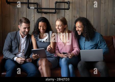 Glückliche junge Leute haben Spaß mit modernen Geräten im Café Stockfoto