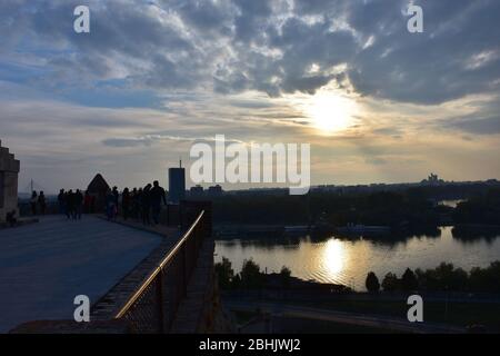 Viele Wanderer auf dem Kalemegdan beobachten den Sonnenuntergang und den von der Sonne erleuchteten Fluss Sava Stockfoto