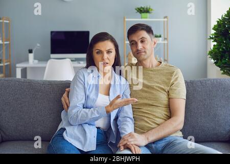 Ein Paar in einer ernsthaften emotionalen Stimmung mit Problemen schaut auf die Kamera, während es auf der Couch sitzt. Stockfoto