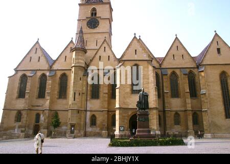 Die lutherische Kathedrale der Heiligen Maria aus dem 12. Jahrhundert in Sibiu, Rumänien. Die Statue des lutherischen Bischofs Georg Daniel Teutsch aus dem Jahr 1899, in der Vorderseite zu sehen Stockfoto