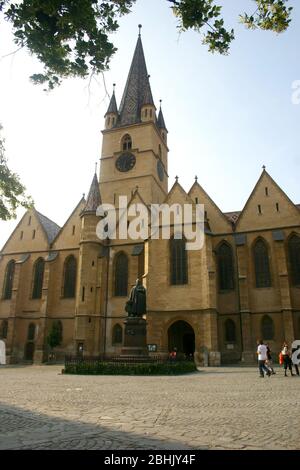 Die lutherische Kathedrale der Heiligen Maria aus dem 12. Jahrhundert in Sibiu, Rumänien. Die Statue des lutherischen Bischofs Georg Daniel Teutsch aus dem Jahr 1899, in der Vorderseite zu sehen Stockfoto