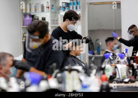 Modin, Israel. April 2020. Israelische Barbiere, die Gesichtsmasken tragen, arbeiten am 26. April 2020 in einem Friseurladen in der zentralisraelischen Stadt Modiin. Alle Straßenläden in Israel, einschließlich Friseur und Schönheitssalons, haben die Genehmigung der Regierung erhalten, ab Samstagabend wieder zu öffnen. (Foto von Gil Cohen Magen/Xinhua) Stockfoto