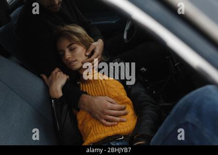 Mann, der ihre schlafende Frau im Auto ansieht und sie mit den Händen berührt Stockfoto