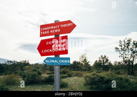 Verschwörungstheorie, Fake News, Covid-19, Panik, Lockdown, globale Krise Straßenwarnschilder. Social Media Kampagne für Coronavirus plus total Stockfoto