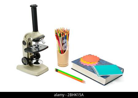 Labormikroskop, Lehrbuch und andere Schulmaterialien auf weißem Hintergrund isoliert. Freier Platz für Text. Stockfoto