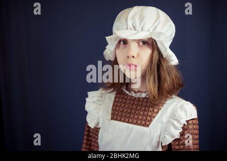 Trauriges Mädchen im viktorianischen Dienstmädchen-Outfit mit Mütze und Schürze Stockfoto