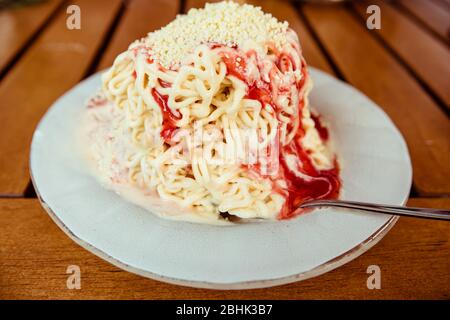 Eine Portion des deutschen Novelty Food Spaghettieis - Vanilleeis und Erdbeersace als Illusion von Spaghetti Stockfoto